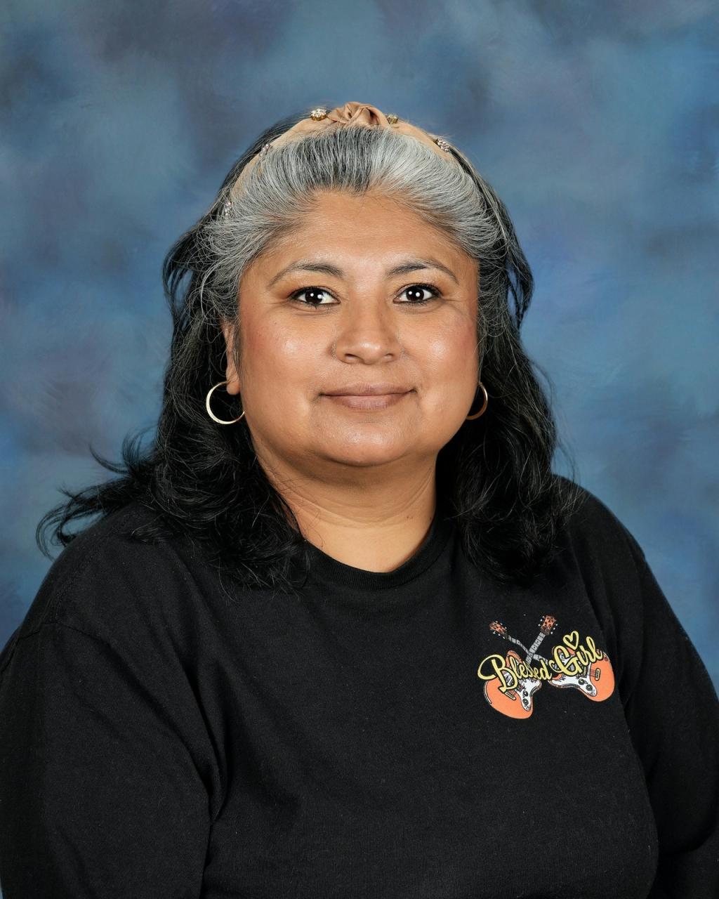 Lady with black hair wearing a black shirt, silver hoop earrings and a headband